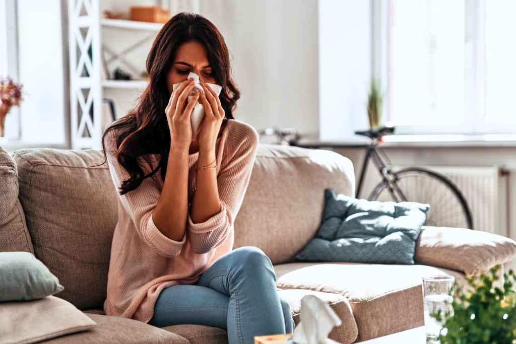 Young woman with a runny nose using a handkerchief, highlighting allergy symptoms worsened by dirty air ducts